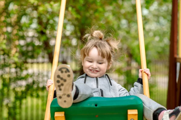 Мила дівчинка на рибальській гойдалці на дитячому майданчику. мила дівчинка на гойдалці бачить. на дитячому майданчику в парку на відкритому повітрі. ходити в дитячому саду — стокове фото