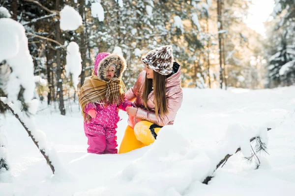 Mor och dotter insvepta i en sjal i en snöig vinterskog. — Stockfoto