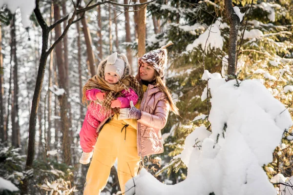 母亲和女儿裹着围巾裹在雪地的冬季森林里. — 图库照片