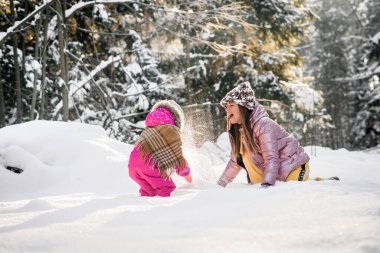 Anne ve kızı karlı bir kış ormanında eşarba sarılı..