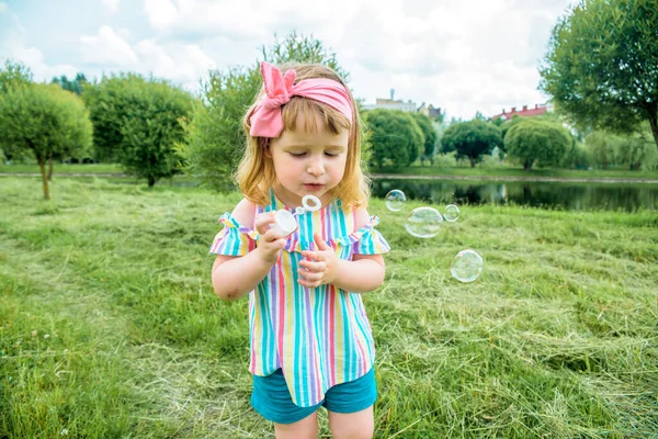 Kleines Schönes kleines Mädchen, das Seifenblasen im Stadtpark Ureki pustet. Ökologie und Natur im Freien. Heißer, sonniger Sommer. glückliche Kindheit, Lebensstil — Stockfoto