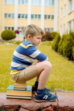 Güzel okul çocuğunun portresi gündüz vakti dışarıda çok mutlu görünüyor. Kitaplar ve okul çantasıyla merdivenlerde oturmak. Okul teması hariç.