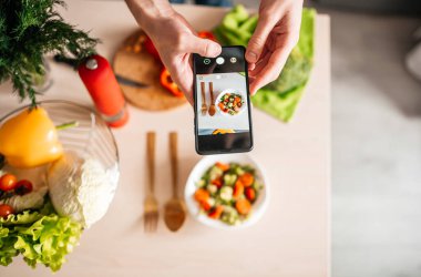 Blogcu adam mutfakta salata fotoğrafı çekiyor. sağlıklı yemek pişirmek .