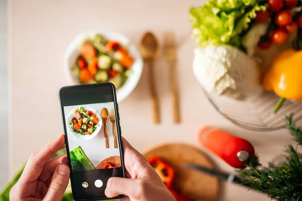 Blogcu adam mutfakta salata fotoğrafı çekiyor. sağlıklı yemek pişirmek .