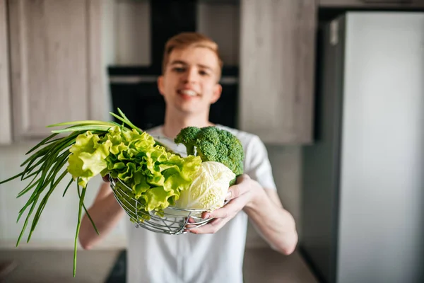 Comida sana y fresca. Hombre joven vegetariano está cocinando ensalada en la cocina interior — Foto de Stock