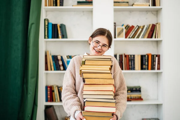 Молода дівчина стоїть біля книжкової полиці в бібліотеці — стокове фото