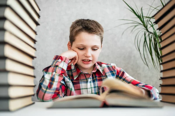 Юропейский мальчик в библиотеке с кучей книг. Підготовка до школи. — стокове фото