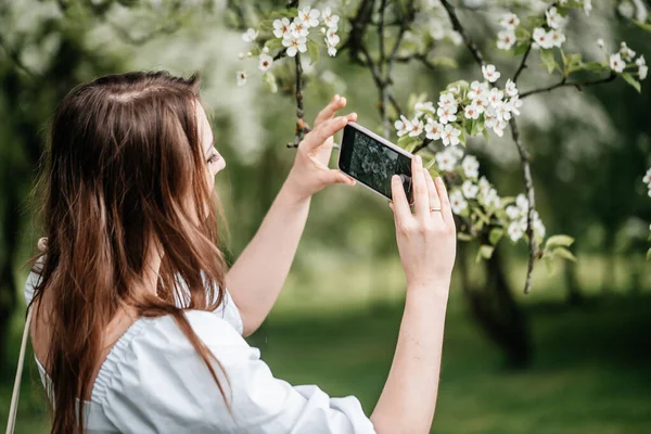 Uma menina com um telefone na mão tira fotos de selfies, fotos para a Internet Fotos De Bancos De Imagens Sem Royalties