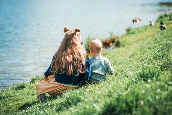 Dos adorables hermanas alimentando patos junto a un río en verano —  Fotos de Stock