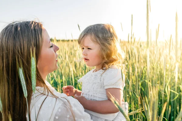 Família feliz, mãe em um vestido com um bebê pequeno bonito em um campo de trigo dourado ao pôr do sol. dia de verão — Fotografia de Stock