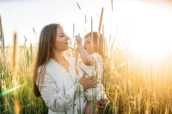 Happy family, mother in a dress with a cute little baby on a golden wheat field at sunset. summer day — Stock Photo, Image