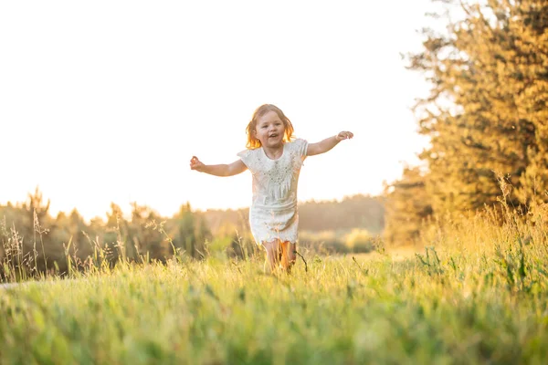 Счастливый ребенок улыбается. маленькая девочка бежит на закате на открытом воздухе — стоковое фото