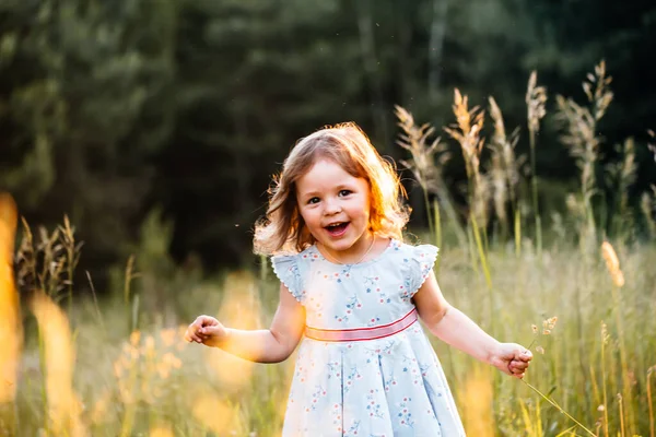 Um bebé feliz a sorrir. menina correndo ao pôr do sol ao ar livre Imagens De Bancos De Imagens