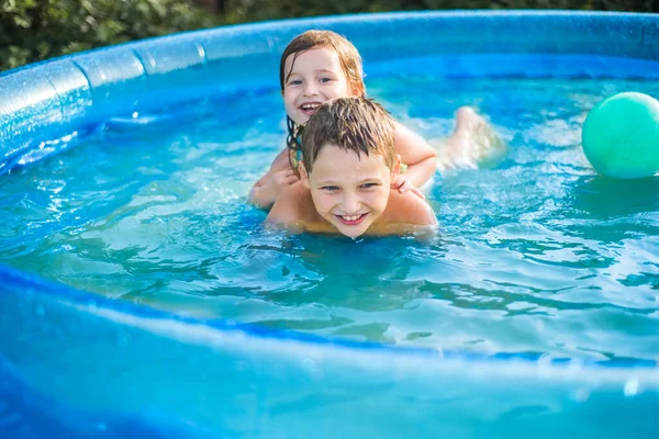Children play with a ball in the pool in hot summer. girl and boy outdoors
