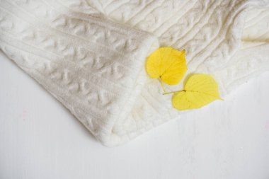 Beyaz örgü kumaş dokusu. Örgü, el yapımı. Sarı sonbahar yaprağı..