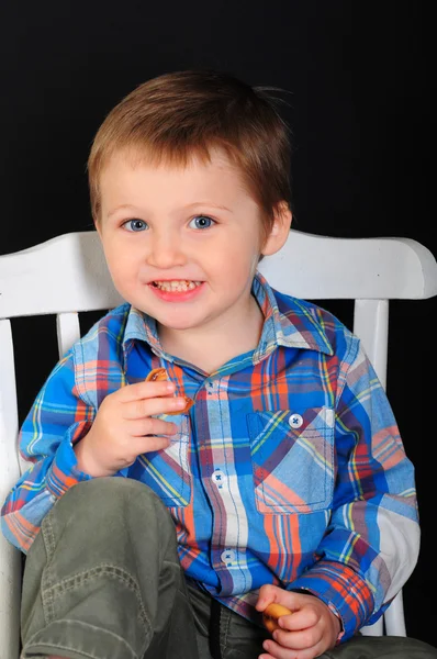 Retrato de um menino louro sorridente em um fundo preto — Fotografia de Stock