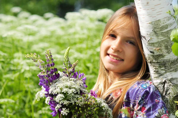 Mooi lachen meisje op een gebied van lupine paarse bloemen. — Stockfoto