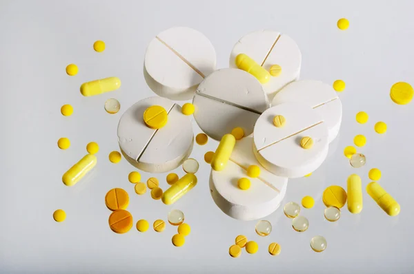 Egy csomó nagy fehér, és egy csomó kis sárga tabletta. — Stock Fotó