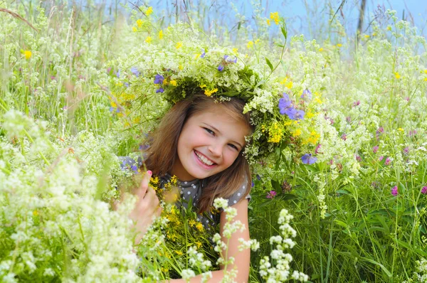 Glücklich lächelndes Mädchen auf einer Wiese. einen Blumenkranz auf ihrem Haupt — Stockfoto