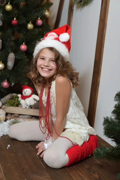 Vacker känslomässiga flicka. I en hemmastudio för nyår och jul. I en vit klänning med en röd rosett och strumpor — Stockfoto