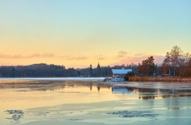 Finlandiya, Turku 'da dondurucu denizin kıyısında gün batımında suda yansımalar görülür. Boşluğu kopyala.