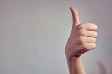 Hafif arka planda baş parmağı olan bir el. Boşluğu kopyala.