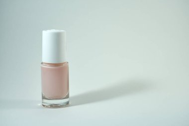 Beyaz arka planda bir şişe pembe tırnak cilası. Boşluğu kopyala.