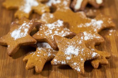 Zencefilli bisküviler ahşap bir tahtanın üzerinde şeker tozuyla kaplıdır..