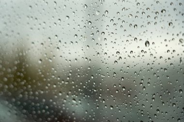   Arka planda bulanık araba olan bardakta yağmur damlaları. Seçici odak.                            