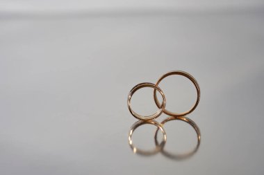   Bulanık gri arka plana yansıyan iki altın alyans                             