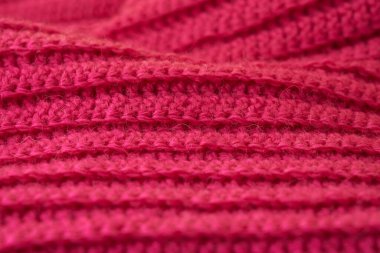 The structure of a knitted canvas of pink wool threads.