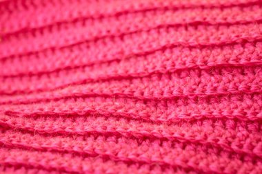 The structure of a knitted canvas of pink wool threads.