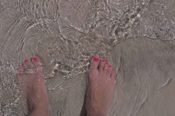 Las piernas de una joven en la playa de cerca. —  Fotos de Stock