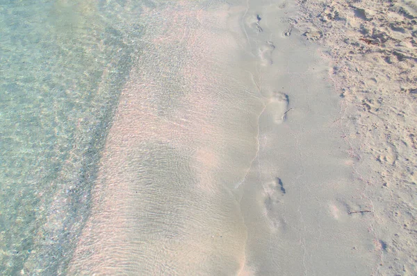 Voetafdrukken op een zandstrand met roze zand. — Stockfoto