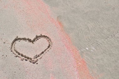 Kalp, deniz kıyısındaki beyaz ve pembe kumlara boyanır.. 