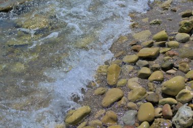 Dalgalar deniz kenarındaki taşlara çarpıyor.