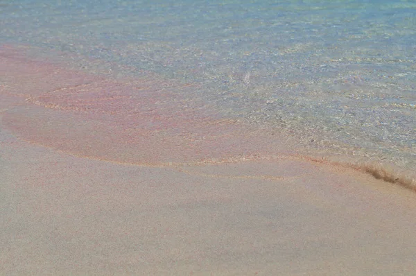 Mała fala morza przykrywa różowy piasek. — Zdjęcie stockowe