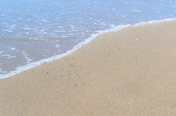Texture di sabbia con un bordo di schiuma d'onda marina. — Foto Stock