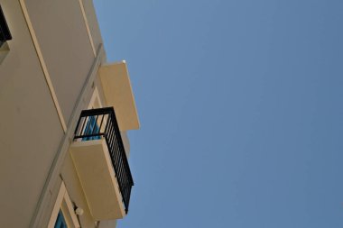 En üst kattaki çok katlı bir binanın balkonunda mavi gökyüzüne karşı..