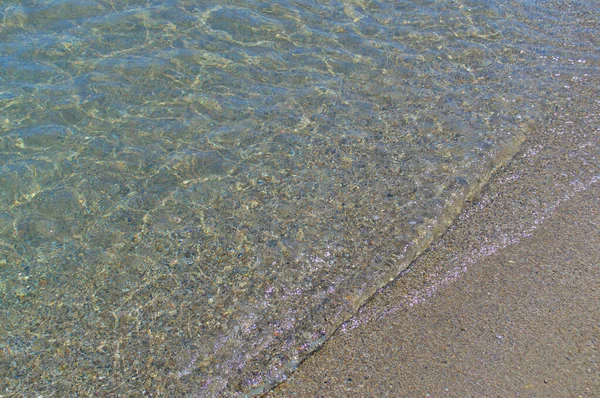 Průhledná mořská vlna na písčitém břehu. — Stock fotografie
