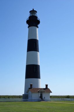 Bodie Adası Deniz feneri açık gökyüzü ve yeşil çimlerle aydınlık güneşli bir günde.