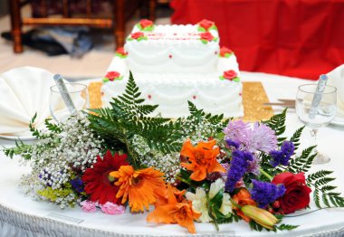 Kutlama, masa örtüsü ve güzel, parlak, renkli çiçeklerle çevrili bir masanın üzerindeki pasta süslemesi. Düğün, nişan, Sevgililer Günü, Anneler Günü, Kadınlar Günü. 