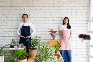 Asyalı yakışıklı bir adam ve güzel bir kadın saksı bitkileriyle ilgileniyor.