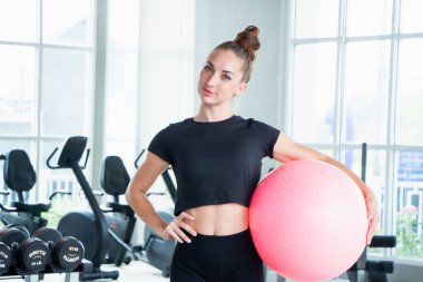 Kafkas beyaz kadın mutlu bir şekilde gülümsüyor yoga minderi ve egzersiz topu tutuyor.