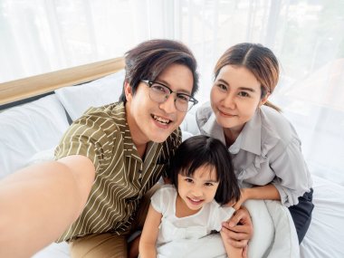 Yatak odasındaki mutlu aile kavramı. Birlikte olmanın tadını çıkarıyorum. Yatakta uzanmak ve selfie çekmek..