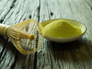 Yeşil çayı kapat, kibrit gücünü arttır ve bir fincan sıcak yeşil çayı ahşap masada çırp. Geleneksel Japon içeceği.