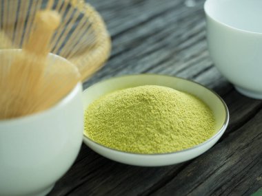 Yeşil çayı kapat, kibrit gücünü arttır ve bir fincan sıcak yeşil çayı ahşap masada çırp. Geleneksel Japon içeceği.