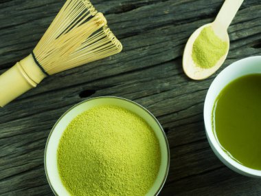 Yeşil çayı kapat, kibrit gücünü arttır ve bir fincan sıcak yeşil çayı ahşap masada çırp. Geleneksel Japon içeceği.