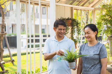 Yaşlı çift, erkekler ve kadınlar saksı diktiler ve arka planda ev diktiler..