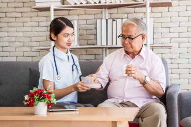 Huzurevi konseptinde kıdemli adam. Hemşireler, huzurevinin oturma odasındaki yaşlılara ilaç verir.